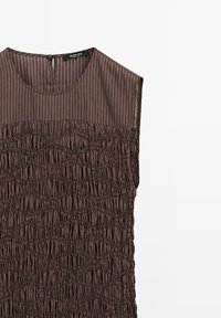 Mouwloze bruine jurk met gestreepte yoke en gerimpeld textuurlichaam, ronde halslijn en knoopsluiting op de achterkant van de hals.