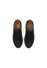 Zapatillas de ante negro con cordones oscuros, plantillas de cuero marrón y suelas de goma blancas. Diseño de punta redonda con un detalle de costura minimalista.