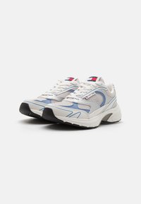 Tenisky s bílou síťovinou, světle modrými detaily a černou gumovou podrážkou. Mezi vlastnostmi se nachází šněrování, polstrovaný jazyk a logo.