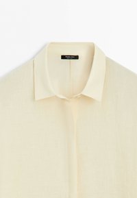 Cream-colored long-sleeve shirt with classic collar and concealed button placket, labeled Massimo Dutti, made in China.