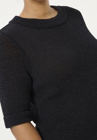 Ciemnogranatowy dziany sweter z krótkimi podwiniętymi rękawami i okrągłym dekoltem. Widoczna faktura tkaniny nadaje mu swobodny wygląd.