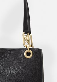 Black leather handbag with textured surface, gold-tone hardware, and a distinctive chain link detail on the strap.