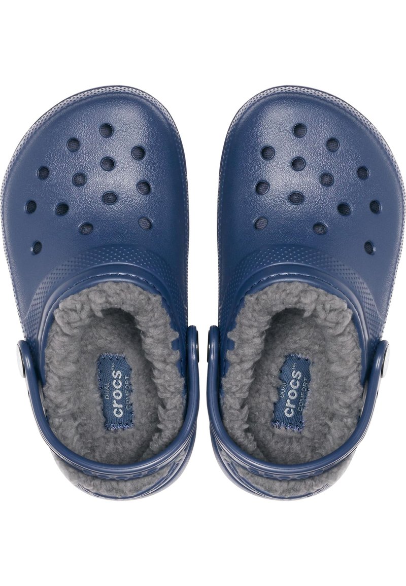 Marineblaue Gummi-Clogs mit Belüftungsöffnungen, weichem grauem Kunstfellfutter und verstellbarem Fersenriemen. Crocs-Logo innen sichtbar.