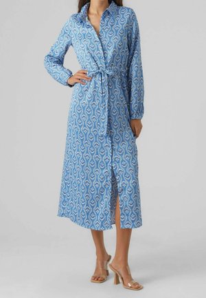 Robe bleue avec motif paisley, manches longues, bouton sur le devant, détail ceinturé à la taille et fente haute jusqu'à la cuisse. Fabriquée en tissu léger.