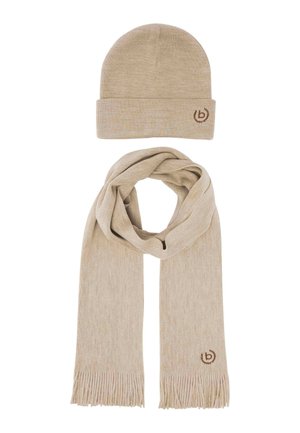 Beige knit beanie hat and matching beige knit scarf with fringe and small brown embroidered logos on white background.