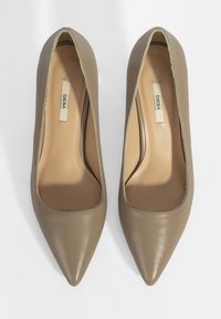 Escarpins beiges en cuir avec un bout pointu, texture lisse et design minimaliste. Intérieur doublé en matériau synthétique nude.