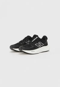 Baskets de sport noires en mesh respirant avec des accents blancs contrastants, dotées d'une pointe arrondie, d'un col rembourré et d'une semelle texturée.