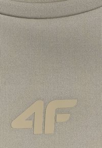 Tissu côtelé gris clair avec logo beige "4F" centré près du bord inférieur, probablement une partie d'un vêtement.