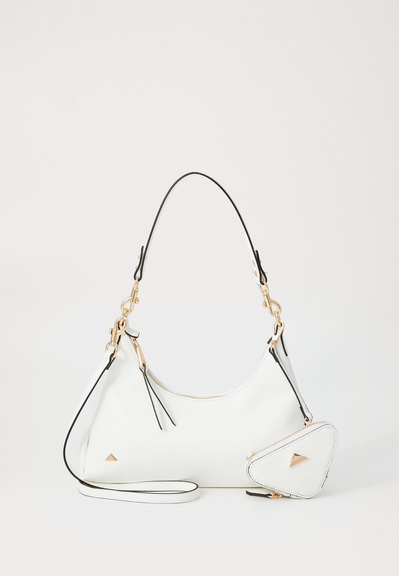 Baltos odos rankinė su juodais akcentais, kreivos formos, auksiniais elementais ir nuimamu trikampiu maišeliu, pritvirtintu su dirželiu.