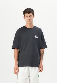 Sort bomulds oversized t-shirt med rund halsudskæring og korte ærmer. Har et lille pink logo på brystet. Enkelt design.