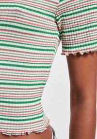 Ribbet cropped topp med horisontale striper i grønn, hvit og rosa, med en bølget hem. Korte ermer og en tettsittende design.