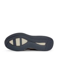 Semelle de chaussure en matériau caoutchouteux gris foncé, présentant des rainures texturées et des accents gris clair, offrant adhérence et durabilité.