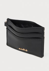 Melna ādas karšu maciņš ar trim karšu nodalījumiem un zelta ALDO logo priekšpusē, attēlots no leņķa uz balta fona.