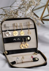 Papuošalų maišelis su smėlio spalvos vidumi, kuriame yra auksinių ir sidabrinių auskarų, vėrinių ir žiedų. Su žemės tema dekoracijomis ir užtrauktuku.