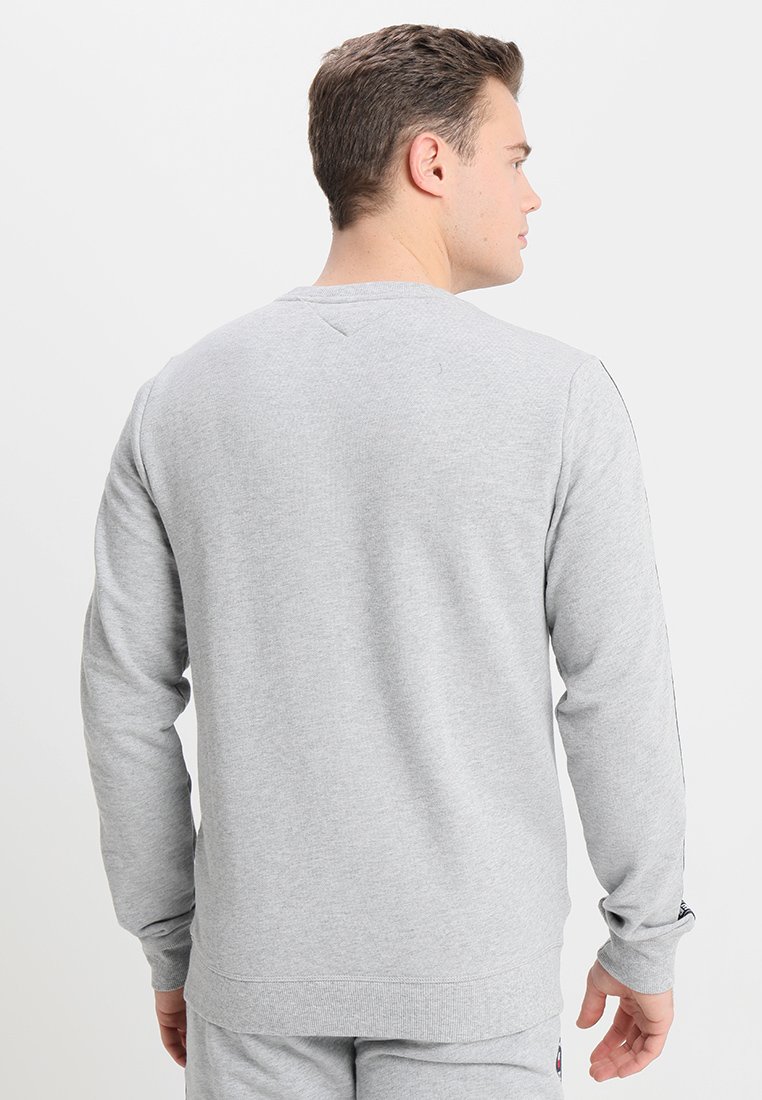 Sweatshirt gris à manches longues en tissu doux, avec un col ras du cou et des poignets côtelés, au design minimaliste sans logos visibles.