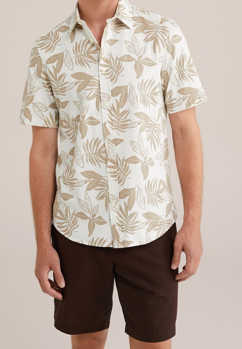 Short-sleeve button-up shirt in light cream with brown leafy pattern; paired with brown shorts; fabric appears lightweight and textured.