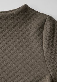 Kangas coklat berbahan tekstur yang menampilkan pola geometris, dengan permukaan halus dan desain yang sedikit timbul, menonjolkan kedalaman dan rincian tekstil.