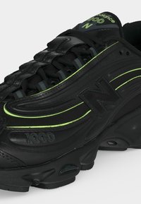 Μαύρο sneaker New Balance 1000 με νεον πράσινες λεπτομέρειες, υλικά από δίχτυ και δέρμα, κλείσιμο με κορδόνια και παχιά μαξιλαρωμένη σόλα.
