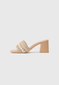 Mule à talon bloc beige avec une large sangle ornée de délicates embellissements en or, argent et teintes pastel dans des motifs de vagues et de zigzags.