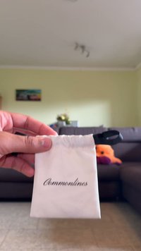 Biały woreczek związywany sznurkiem z napisem "Commonlines" wydrukowanym na czarno. Posiada czarny sznurek do zamykania. Trzymany ręcznie na tle.