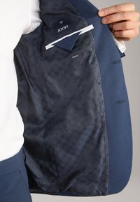 Granatowa marynarka z wzorzystą podszewką, z etykietą slim fit i kieszenią z wytłoczonym logo. Gładka faktura materiału.