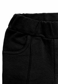 Czarne bawełniane spodnie dresowe z elastycznym pasem, bocznymi kieszeniami i miękką teksturą. Projekt jest prosty i funkcjonalny.