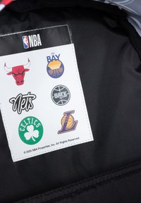 Zwarte stoffen label met zes NBA-teamlogo's: Chicago Bulls, Golden State Warriors, San Antonio Spurs, Boston Celtics, Brooklyn Nets en Los Angeles Lakers.