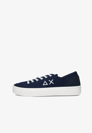 Zapatillas de lona azul marino con cordones blancos y suela de goma. Presenta un logo geométrico blanco en el lado exterior y acentos en el talón en azul oscuro que contrastan.
