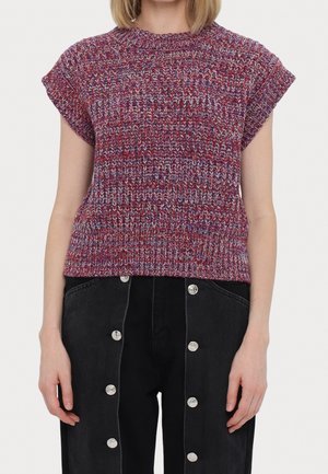 Multifarvet strikket kortærmet sweater kombineret med sorte bukser med høj talje med to lodrette rækker af sølvknapper.