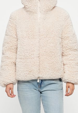 Giacca soffice color crema con cerniera e maniche lunghe indossata con jeans denim azzurri chiaro, mostrata dalle spalle ai fianchi.