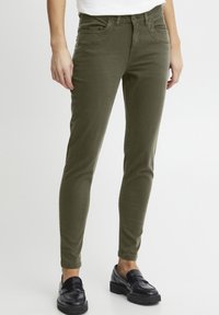 Maslinasto zelene skinny traperice izra�đene od mekanog materijala, s dva prednja džepa, džepići za novčiće i kopčom na dugme. Glatki, podesivi pojas.