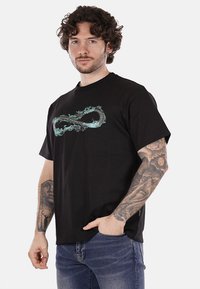 T-shirt nera in cotone con design infinito turchese sul davanti. Maniche corte, scollatura rotonda, vestibilità relax.