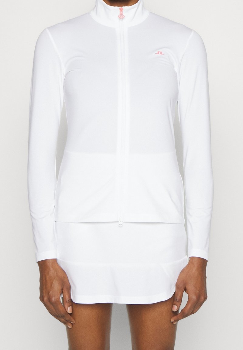 White long-sleeve zip-up top with high collar, made from smooth, lightweight fabric. Features subtle logo and contrasting zipper detail.