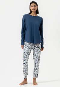 Haut à manches longues bleu marine associé à un pantalon à imprimé floral en blanc, bleu et vert. Tissu doux avec une coupe décontractée.