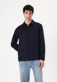 Navyblauwe button-up shirt van katoen, met een kraag, twee voorzakken en een kleine gele logo-detail op de mouw.