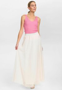 Roze geribbelde tanktop met een V-hals, gecombineerd met een lange, doorzichtige, lichtgekleurde maxi-jurk met een elastische tailleband.