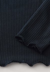 Rippstoff in dunklem Marineblau mit strukturierter Oberfläche, ausgestattet mit gewellten Kanten an den Bündchen, die ein weiches, dehnbares Strickdesign präsentieren.