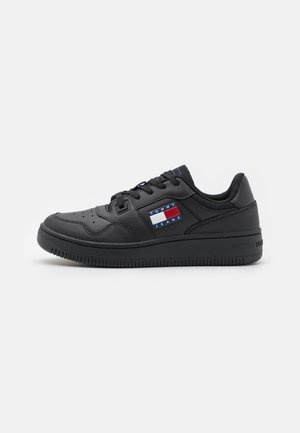 Czarny niski sneaker z sznurowaniem z przodu i naszywką z logo Tommy Jeans po boku, pokazany na jednolitym białym tle.