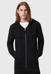 Black zip-up hoodie made of soft fabric with a front kangaroo pocket, drawstring hood, and a small logo on the chest.