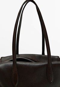 Dark brown textured leather handbag with two long handles and a partially open zipper on top against a white background.