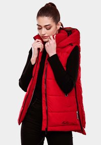 Gilet rembourré rouge avec capuche amovible, doté d'une fermeture éclair à l'avant, de poches latérales et d'un design qui met en valeur la silhouette. Manches côtelées noires visibles.
