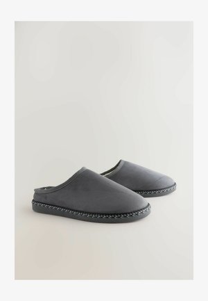 Zapatillas de ante gris con punta cerrada, forro interior suave y un ribete trenzado decorativo a lo largo de la suela. Sin cierres visibles.