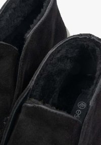Czarne zamszowe botki za kostkę z miękkim, puszystym wykończeniem wewnętrznym oraz pikowanymi detalami, z gładkim, zaokrąglonym noskiem i subtelnym logo.
