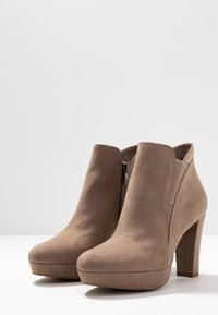 Beige mokkasinit korkean tukkikannan avulla, pyöreällä kärjellä ja sivuvetoketjulla. Suunnitelmassaan on sileä pinta ja minimimaljakat.