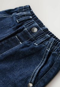 Pantalones cortos de mezclilla con cintura elástica, color azul oscuro, costuras blancas contrastantes y un detalle de botón plateado.
