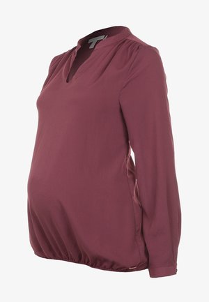 Maternity blouse in burgundy, featuring long sleeves, a v-neckline, and a gathered hem for comfort and fit. Made of soft, lightweight fabric.