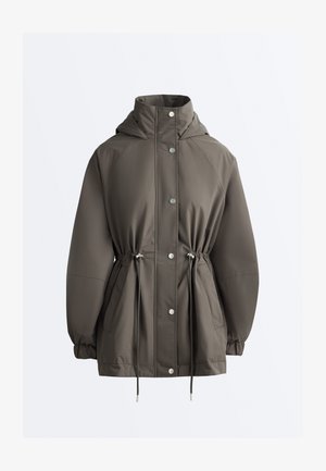 Kurtka z kapturem w ciemnooliwkowym kolorze, zapinana na zatrzaski, z regulowanym sznurkiem w talii, elastycznymi mankietami i przednimi kieszeniami.