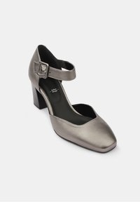 Chaussure Mary Jane en cuir gris métallique avec talon bloc et sangle à boucle ajustable sur fond blanc.
