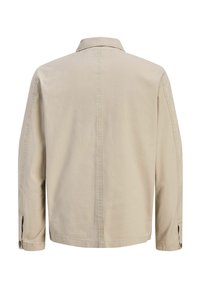 Φωτεινό μπεζ βαμβακερό πουκάμισο-ζακέτα με γιακά, μακριά μανίκια και κουμπιά στα μανσέτα· διαθέτει καθαρές γραμμές και μινιμαλιστικό σχέδιο.