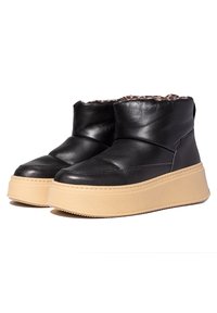 Botines negros con parte superior acolchada, suelas de plataforma en beige y suave forro de piel en el interior, diseñados para el clima frío.